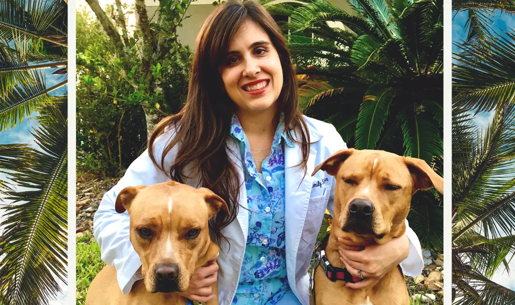 Photo of IndeVets employee posing with two reluctant dogs