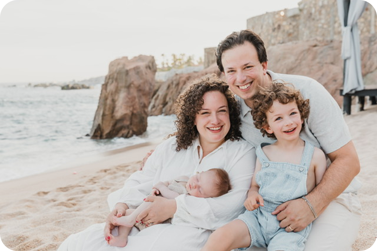 Dr. Sam Cantor, her husband, and two children posing for a photo on a beach.