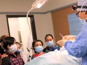 Photo of Dr. Tuma demonstrating surgery to a group of children.