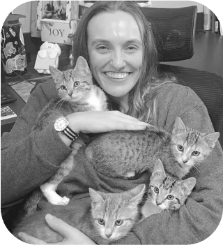Photo of veterinarian Sara Davis holding several kittens in her arms.