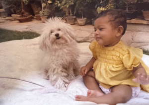 Dr. Sreerama as a baby sitting beside a small fluffy white dog